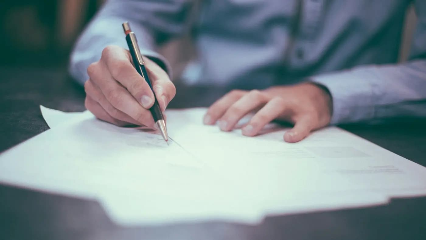 Hand signing a document on a desk