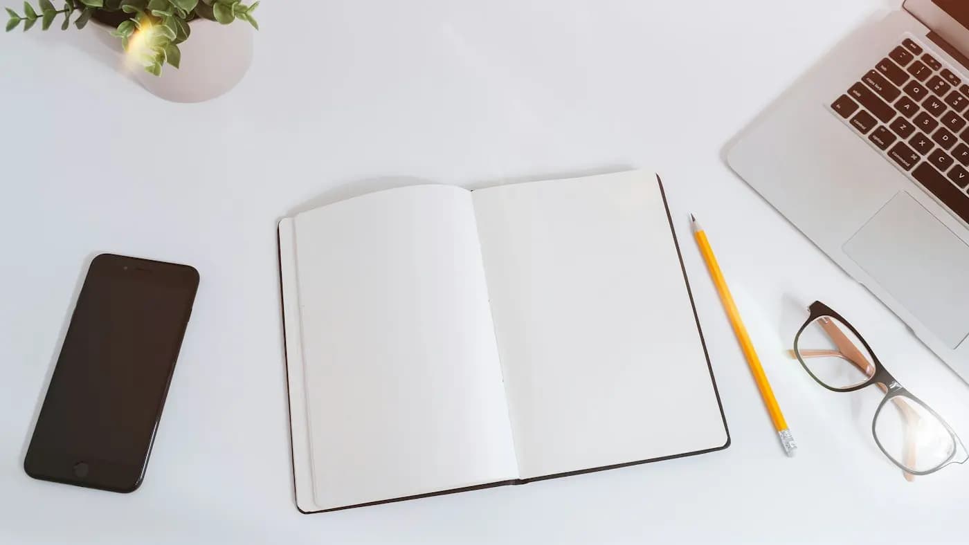 Blank open notebook with a pencil on a white desk