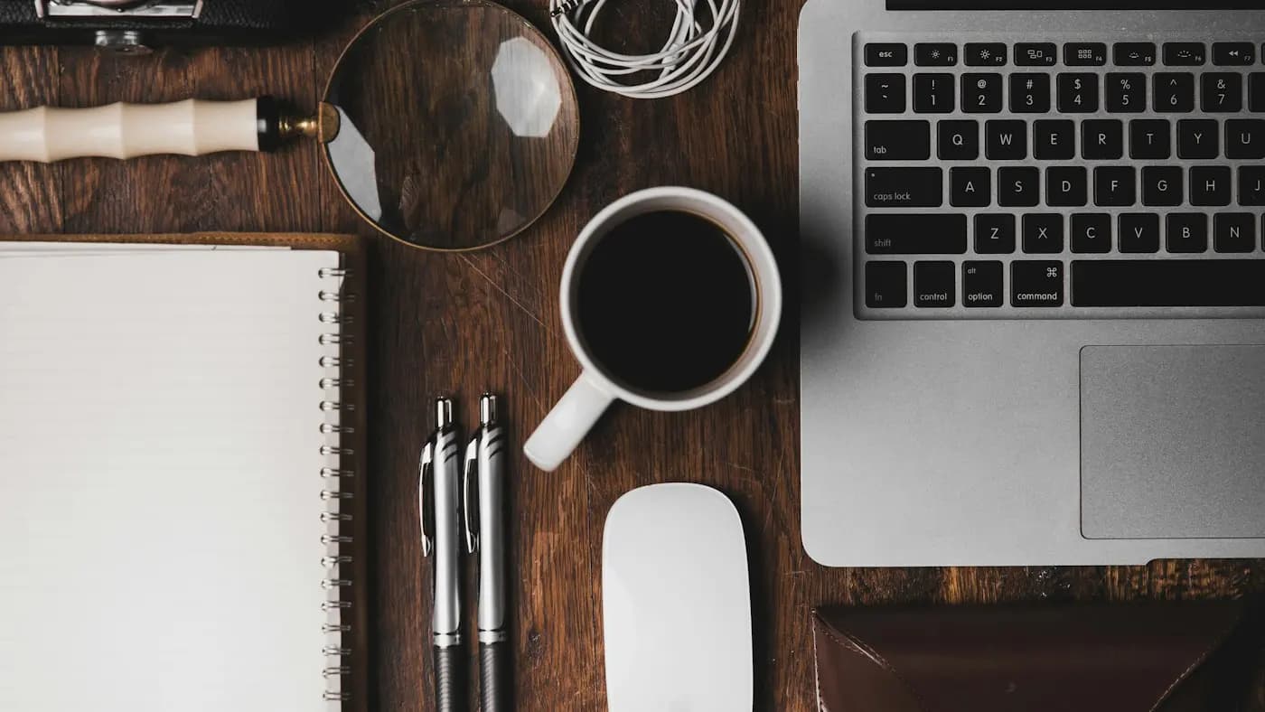 Desk with laptop, coffee and stationery from above