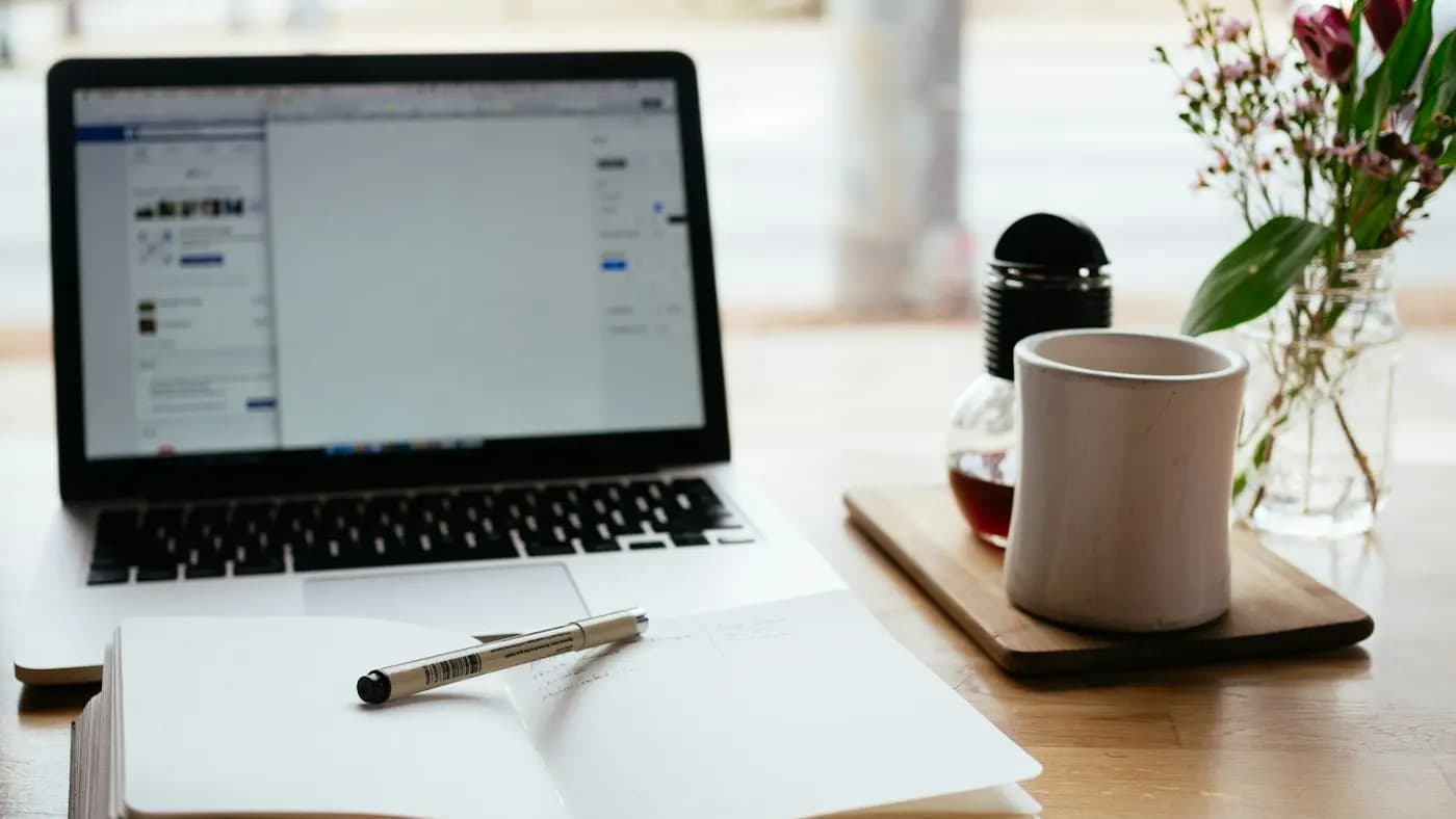 Open notebook, pen and laptop on a desk