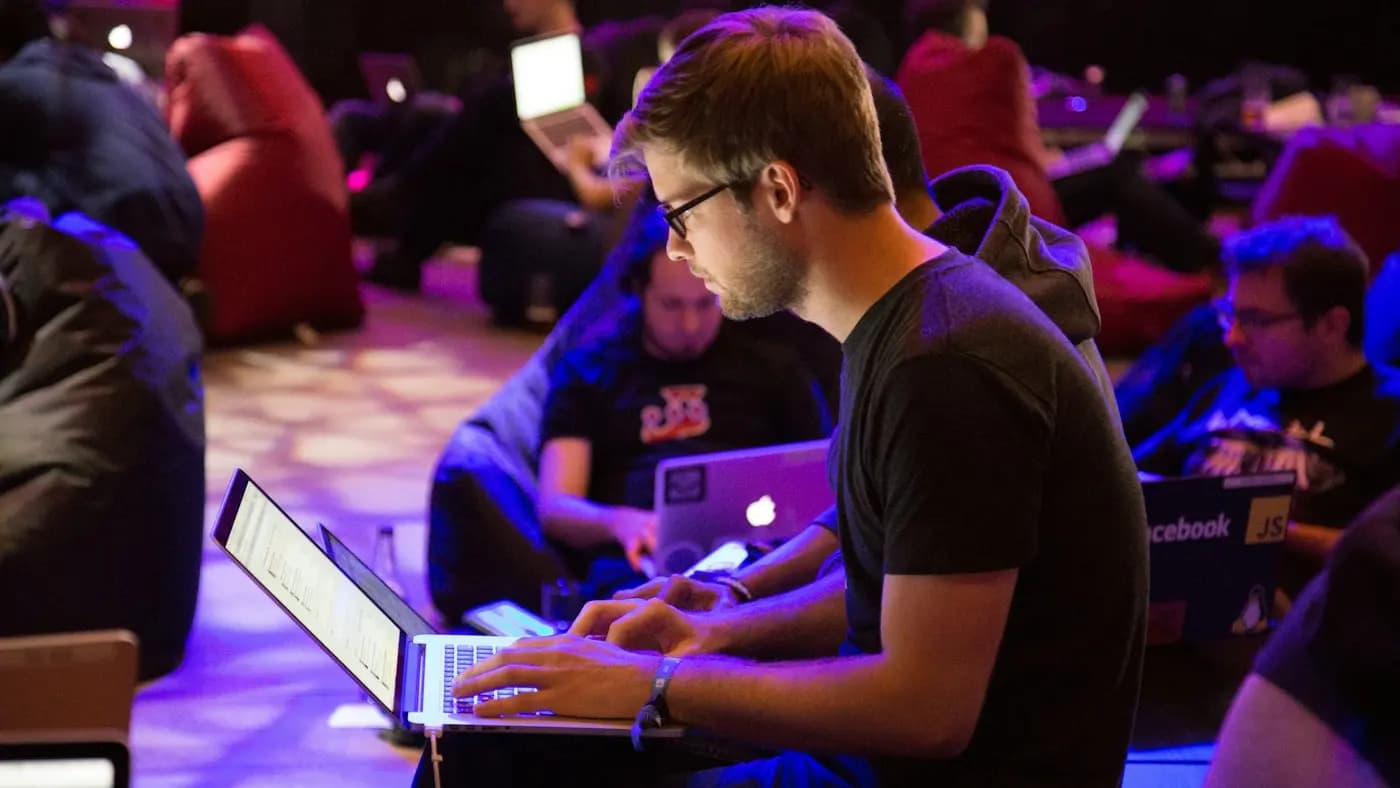 Man working on a laptop at a busy event