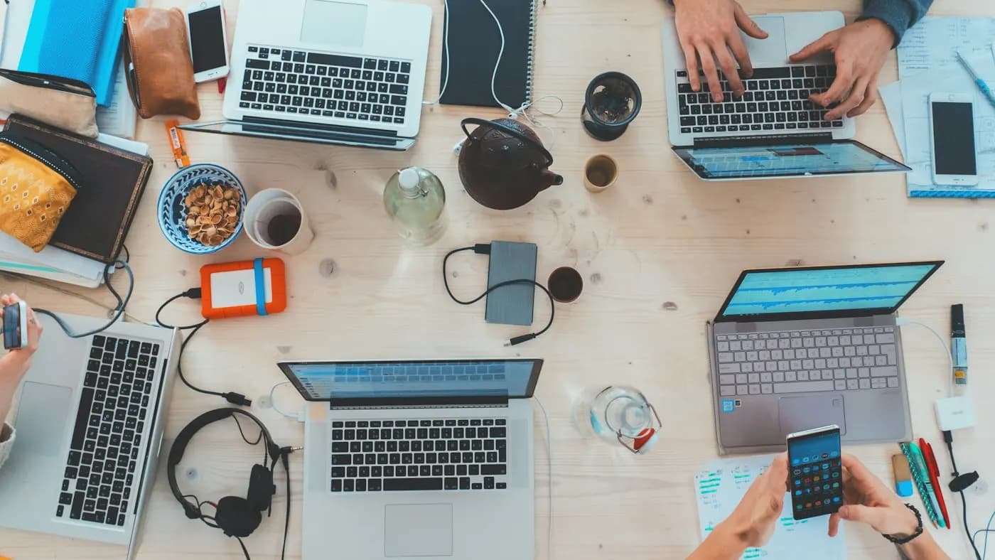 Top view of a desk with several laptops and notebooks