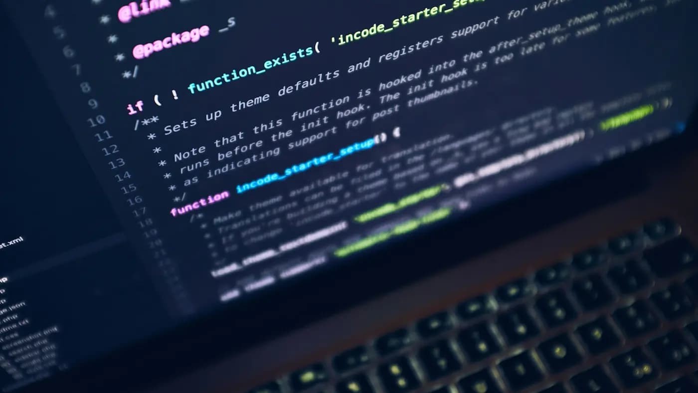 Laptop screen showing lines of website code in a dark editor